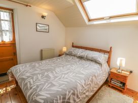 A bedroom with a wooden bed and bedside tables under a skylight window at Arfron Penrhyddion Pella in Capel Garmon near Betws-y-Coed