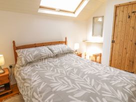 A bedroom with a wooden bed a bedside table with lamp a skylight and a wooden door at Arfron Penrhyddion Pella in Capel Garmon near Betws-y-Coed