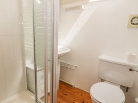 A bathroom with a shower enclosure a toilet a sink and a wooden floor at Arfron Penrhyddion Pella in Capel Garmon near Betws-y-Coed