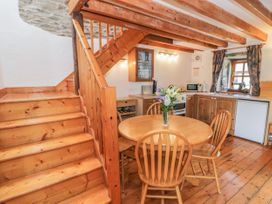 A kitchen with wooden dining table and chairs and a staircase at Arfron Penrhyddion Pella in Capel Garmon near Betws-y-Coed