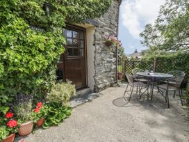 An outdoor seating area with a metal table and four chairs next to a stone wall door with plants and flowers at Arfron Penrhyddion Pella in Capel Garmon near Betws-y-Coed