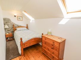 A small bedroom with a wooden bed and chest of drawers under skylights at Meifod Penrhyddion Pella in Capel Garmon near Betws-y-Coed
