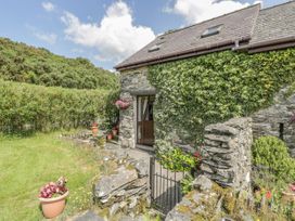 An exterior view of a stone cottage with ivy on the wall and a garden gate at Bwthyn Penrhyddion Pella in Capel Garmon near Betws-y-Coed