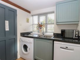 A kitchen with a washing machine, sink, microwave and dishwasher at Sleepeezy in Little Snoring