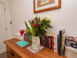 A table with a vase of flowers and books in the hallway at Berry Banks Cottage, Whitby