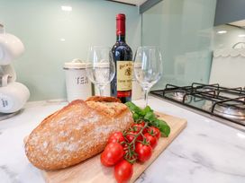 A kitchen counter with bread, wine, and glasses at Berry Banks Cottage in Whitby