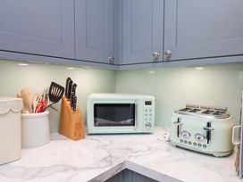 A kitchen with a microwave, toaster, and utensils at Berry Banks Cottage in Whitby