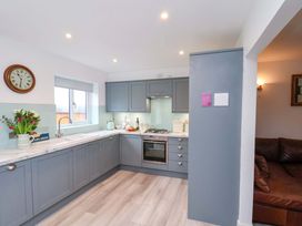 A kitchen with cabinetry and appliances at Berry Banks Cottage Whitby