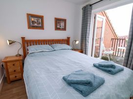 A bedroom with a bed and sliding door leading to a balcony at Berry Banks Cottage in Whitby