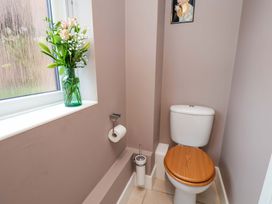 A bathroom with a toilet and a vase of flowers at Berry Banks Cottage in Whitby