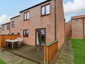 An outdoor area with a wooden deck and furniture at Berry Banks Cottage in Whitby