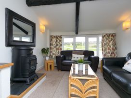 A living room with two black leather sofas a glass coffee table a black stove and a large mirror at Harrisons Cottage in Llandegla near Llangollen