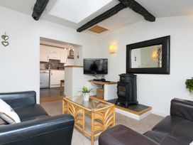 A living room with a stove a glass table and black leather sofas at Harrisons Cottage in Llandegla near Llangollen
