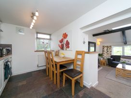 A dining area with a wooden table and chairs next to a kitchen and adjacent living room at Harrisons Cottage in Llandegla near Llangollen