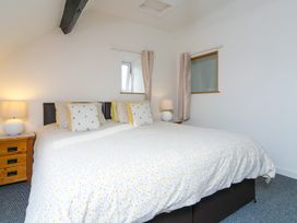 A bedroom with a large bed two bedside tables with lamps and two small windows at Harrisons Cottage in Llandegla near Llangollen