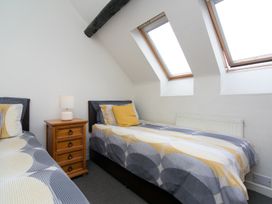 A bedroom with two single beds separated by a wooden nightstand with a lamp under skylight windows at Harrisons Cottage in Llandegla near Llangollen
