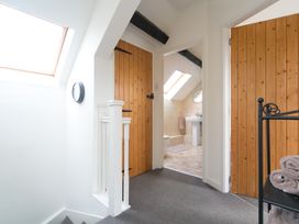 A hallway with two wooden doors a view into a bathroom skylights and a black metal towel rack with towels at Harrisons Cottage in Llandegla near Llangollen