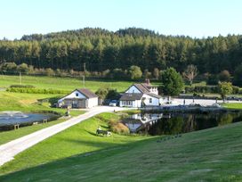 A rural property with white houses near a pond and surrounded by grassy fields and trees at Harrisons Cottage in Llandegla near Llangollen
