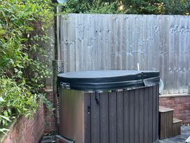 A hot tub with a chimney and wooden steps in an outdoor area at Treetops near Sidmouth