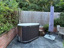 A garden with a hot tub and wooden bench at Treetops Southerton near Sidmouth