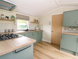 A kitchen with green cabinets wooden countertops a gas stove a sink and shelves with kitchen items at The Four Oaks Chalet in Blaich near Fort William