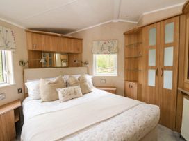 A bedroom with a double bed two windows wooden cupboards and bedside tables at The Four Oaks Chalet in Blaich near Fort William