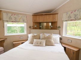 A bedroom with a bed between two windows and wooden cabinets above the bed at The Four Oaks Chalet in Blaich near Fort William