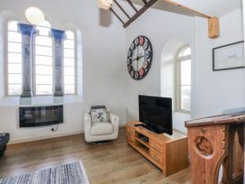 A living room with a television and fireplace at Eglwys St Cynfil Penrhos near Pwllheli
