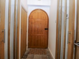 A hallway with wooden doors and a door mat at Eglwys St Cynfil Penrhos near Pwllheli