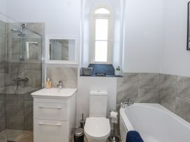 A bathroom with a shower, vanity, toilet and bathtub at Eglwys St Cynfil Penrhos near Pwllheli