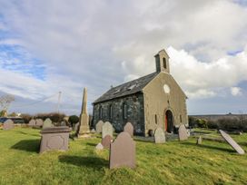 A church with gravestones in the foreground at Eglwys St Cynfil in Penrhos near Pwllheli