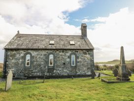 An outdoor view of a stone building and tombstones at Eglwys St Cynfil in Penrhos near Pwllheli