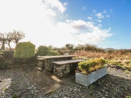 A garden area with a stone table and benches at Eglwys St Cynfil Penrhos near Pwllheli