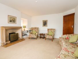 A living room with floral armchairs and sofa a fireplace wooden door and bookshelf at Bryn Eithin in Borth-y-Gest near Porthmadog