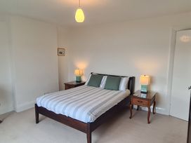 A bedroom with a double bed with striped bedding and two nightstands with lamps at Bryn Eithin in Borth-y-Gest near Porthmadog