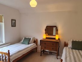 A bedroom with two single beds and a wooden dresser with two lamps at Bryn Eithin in Borth-y-Gest near Porthmadog