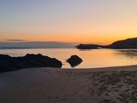 A beach with rocks and calm water during sunset at Bryn Eithin in Borth-y-Gest near Porthmadog
