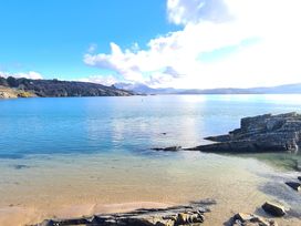 A coastal scene with a sandy beach rock formations and hills in the distance at Bryn Eithin in Borth-y-Gest near Porthmadog