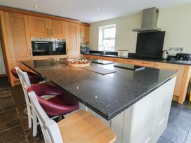 A kitchen with wooden cabinetry and a central island at Chapel House Elim near Llanddeusant