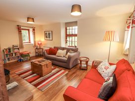 A living room with a sofa, armchair, and bookshelf at The Old Bothy Bolton Low Houses near Wigton