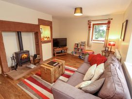 A living room with a wood stove and television at The Old Bothy in Bolton Low Houses near Wigton