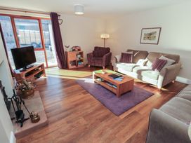 A living room with a sofa, armchair, and television at The Old Grainstore in Bolton Low Houses near Wigton