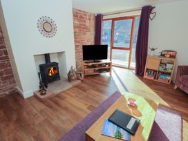 A living room with a fireplace and television at The Old Grainstore Bolton Low Houses near Wigton