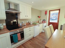 A kitchen with appliances and dining area at The Old Grainstore Bolton Low Houses near Wigton