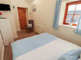 A bedroom with a bed and chair at The Old Grainstore in Bolton Low Houses near Wigton