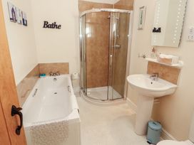 A bathroom with a bathtub, shower, and washbasin at The Old Grainstore Bolton Low Houses near Wigton