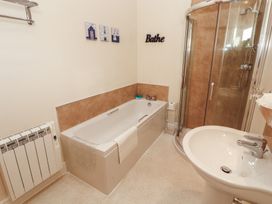 A bathroom with a bathtub, shower and sink at The Old Grainstore Bolton Low Houses near Wigton