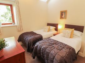 A bedroom with two single beds and a window at The Old Grainstore Bolton Low Houses near Wigton