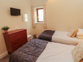 A bedroom with two single beds and a dresser at The Old Grainstore Bolton Low Houses near Wigton