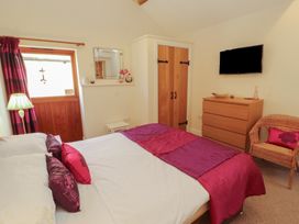 A bedroom with a bed and wardrobe at The Old Grainstore Bolton Low Houses near Wigton